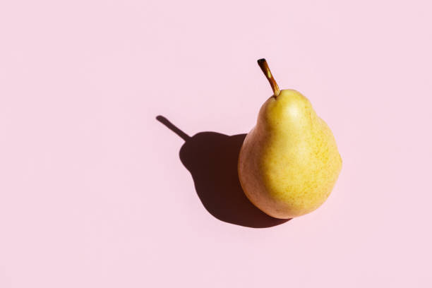 Ripe pear with dark shadows on pink color background. Food blog, vegetable background. Ripe pear with dark shadows on pink color background. Food blog, vegetable background. harsh shadows stock pictures, royalty-free photos & images