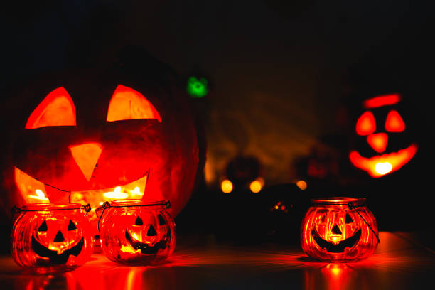 istock Many Halloween Pumpkin glowing faces in a row on dark black background. greeting card 1255158552