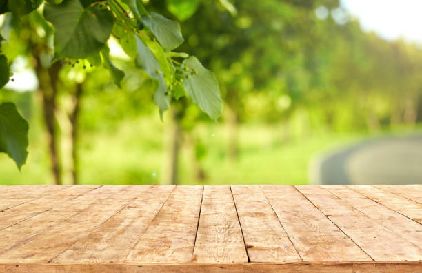 istock Mockup. Empty wooden deck table with foliage bokeh background. 1255161936