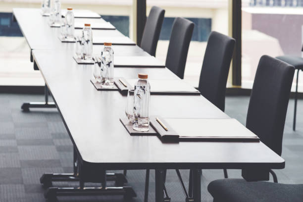istock Plastic water bottles, Drinking glasses with pencil and white papers setup on the table prepared for seminar or business meeting in the hotel conference room 1255162900