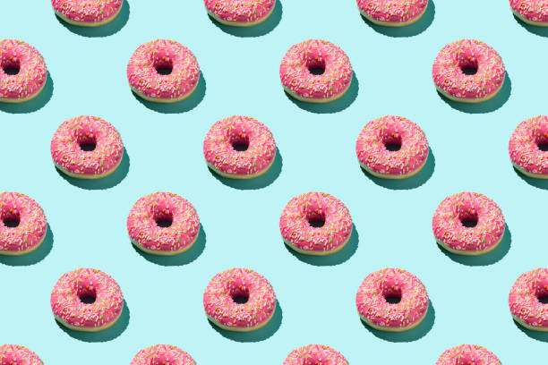 istock Flat lay pattern of tasty pink colorful donut on blue background. 1255164546