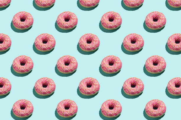 istock Flat lay pattern of tasty pink colorful donut on blue background. 1255164548