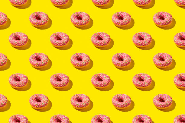 istock Flat lay pattern of tasty pink donut on yellow background. 1255164779