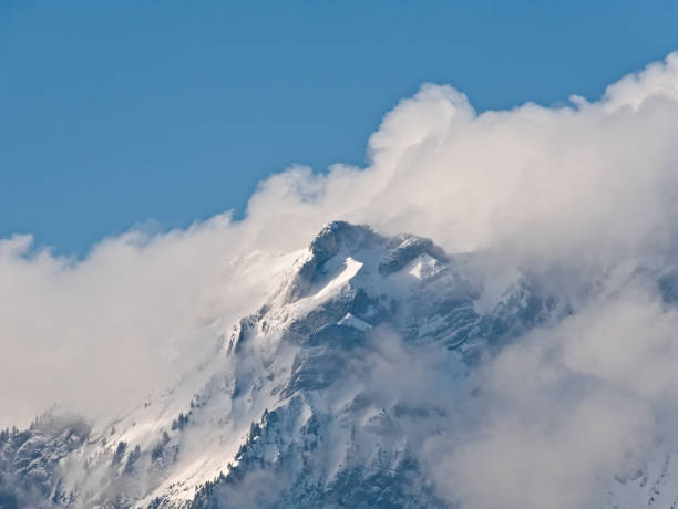 istock snow-covered rock sticks out of clouds 1255169182