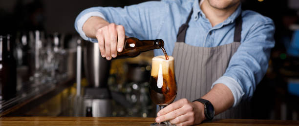 istock Client order at pub. Bartender pours dark beer in glass at bar 1255169244
