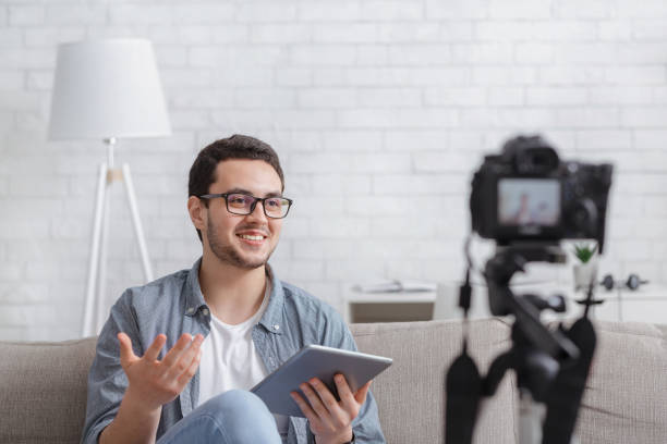 istock Streaming online podcast. Modern man with tablet makes recording video 1255170564