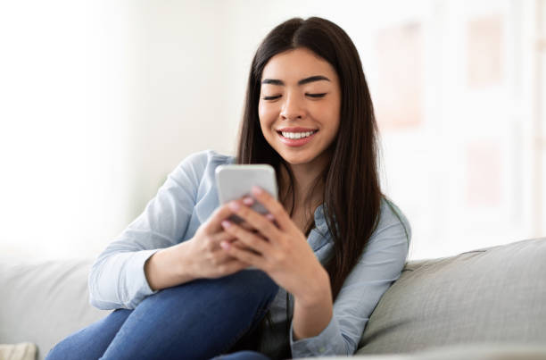 istock Smiling Asian Girl Using Smartphone At Home, Checking Social Media 1255170734