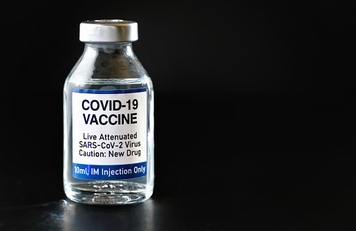 Coronavirus Covid 19 vaccine concept (own design, not real product) - small glass bottle with silver cap, closeup detail on black background