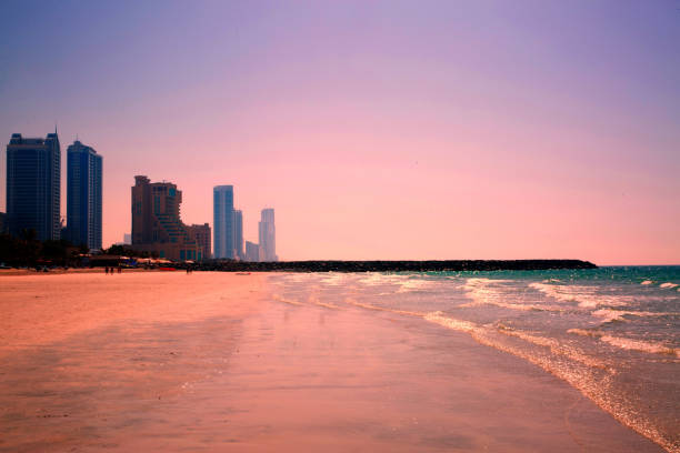 Beautiful violet pink sunset at the beach, modern skyscrapers. Empty beach.