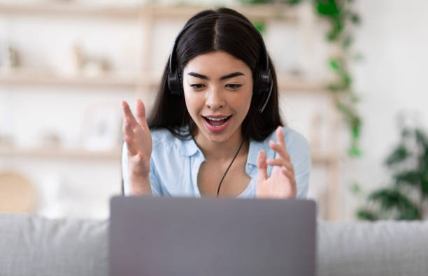 istock Video Conference. Asian girl having web call on laptop computer at home 1255171815