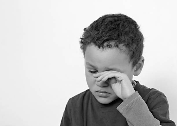 boy crying in poverty with no help crying alone and all by himself on white background stock photo
