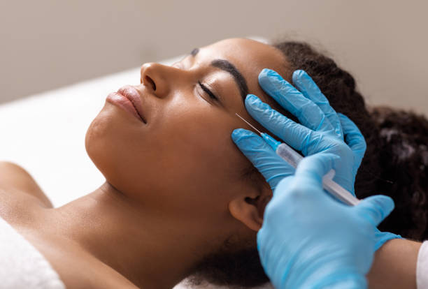 istock Beautician making eye beauty injection for young african lady 1255173629