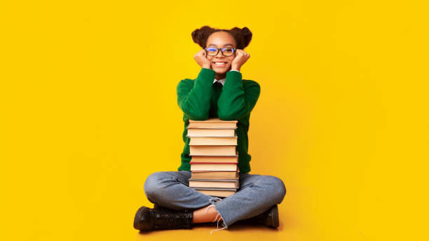 istock Afro schoolgirl with pile of books at studio 1255175229