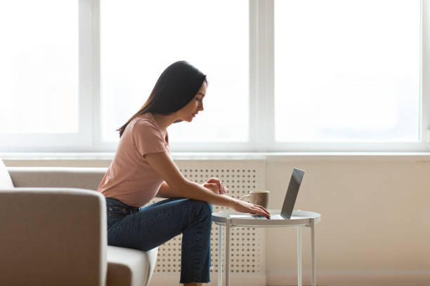 istock Female Freelancer Working On Laptop Sitting Near Window Indoor, Side-View 1255176725