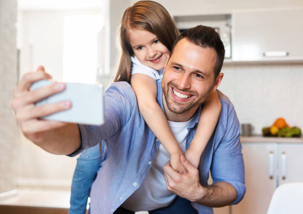 istock Cheerful Dad And Daughter Making Selfie Having Fun In Kitchen 1255176753