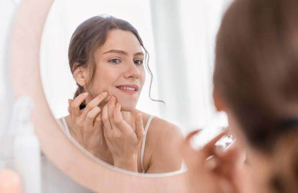Girl Looking In Mirror and Touching Pimple