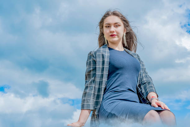istock A young girl climbed a cloud and has fun there as her heart desires. 1255178367