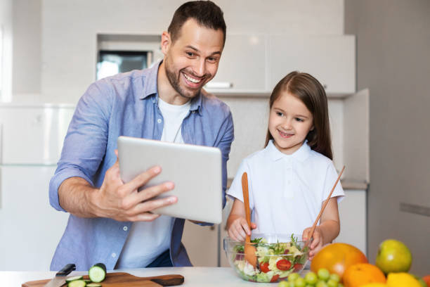 istock Father And Daughter Using Tablet Cooking In Kitchen At Home 1255178610