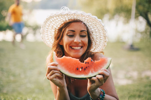 istock A young woman laughs and eats watermelon in nature 1255178984