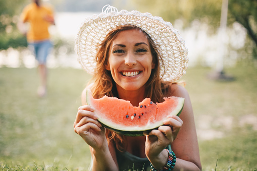 Young woman looking at camera and eating watermelon in nature