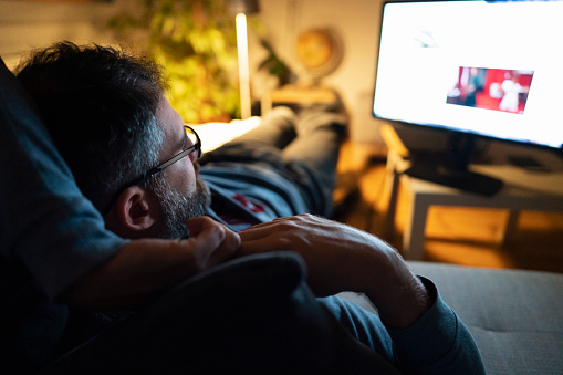 Relajado hombre de mediana edad viendo la televisión por la noche photo