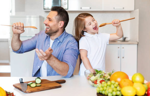 istock Father And Daughter Having Fun Cooking Together Singing In Kitchen 1255181653