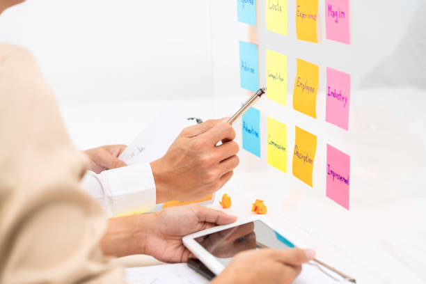 istock Creative group of business people brainstorming use sticky notes to share idea on glass window or table in office 1255182035