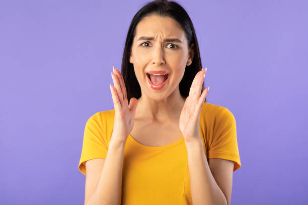 istock Young female grimacing, screaming at purple studio 1255182218