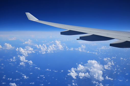 Airplane wing seen from inside the craft, clear blue sky above the clouds