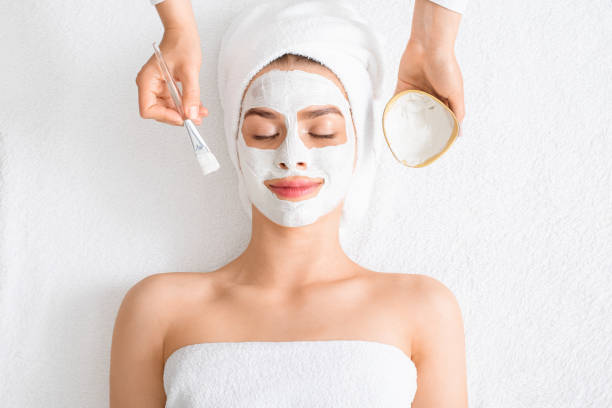 de therapeut die van de spa gezichtsmasker voor jonge dame zet - masker stockfoto's en -beelden