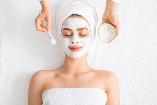 spa therapist putting facial mask for young lady - face mask imagens e fotografias de stock