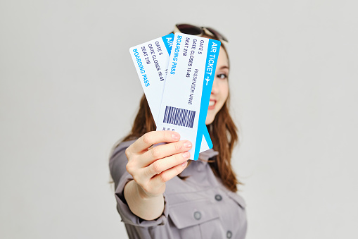 Girl holds forward plane tickets with a smile. Close up.