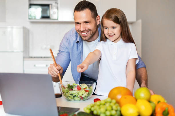 istock Cute Father And Daughter Cooking Using Laptop Together In Kitchen 1255189858