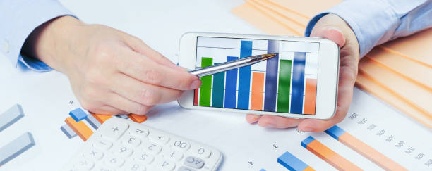 istock Finance. Female hand with calculator on financial graphs on desk 1255192830