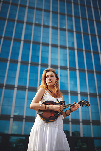 Shot of a beautiful young woman out in the city with her guitar