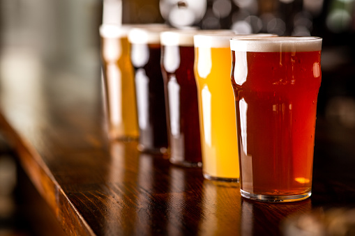 Big choice of beers. Drinks of different colors on wooden bar counter, close up, free space