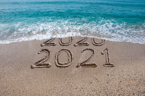 New year 2021 written on sandy beach with waves