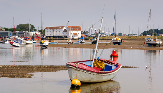 Safety boat lies in shallow water in front of the tide mill at Woodbridge on the Deben Estuary in Suffolk UK