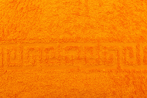 Terry towel, texture, textile background close up. Terry orange towel background. Color orange terry towel made of cotton fabric. Structure with uncut thread loops. orange towel background.