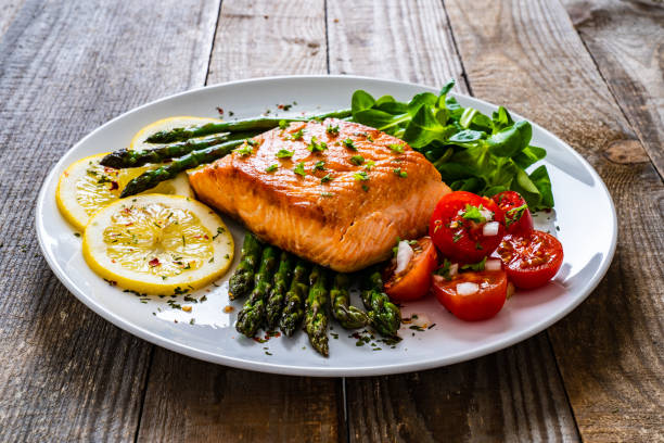 istock Fried salmon steak and asparagus on wooden table 1255205282