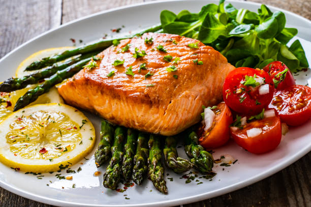 istock Fried salmon steak and asparagus on wooden table 1255205319