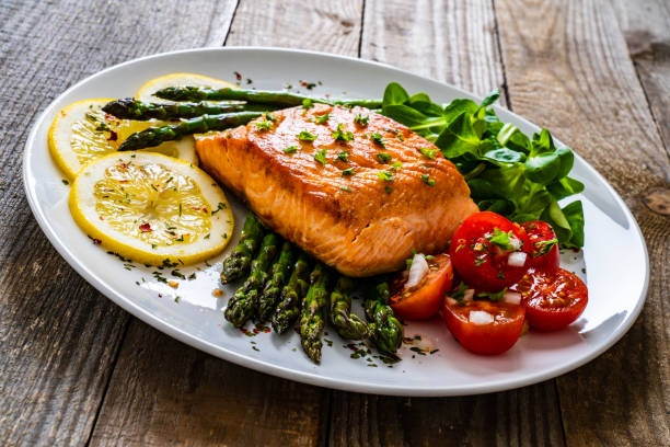 istock Fried salmon steak and asparagus on wooden table 1255205360