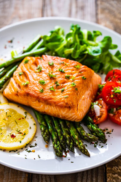 istock Fried salmon steak and asparagus on wooden table 1255205404