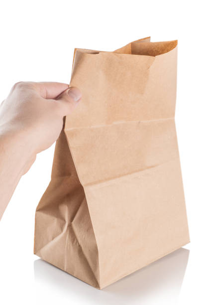 istock Brown paper bag isolated on white background. brown craft package in hand 1255208251
