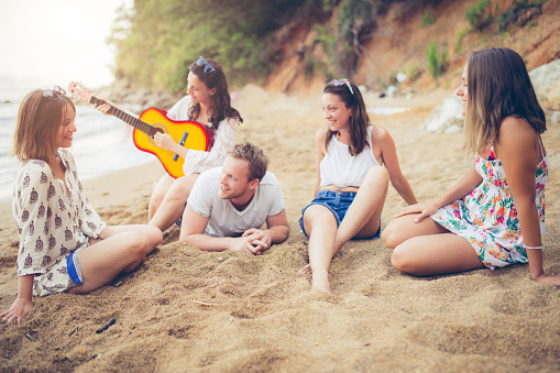 Young people making beach party with guitar.