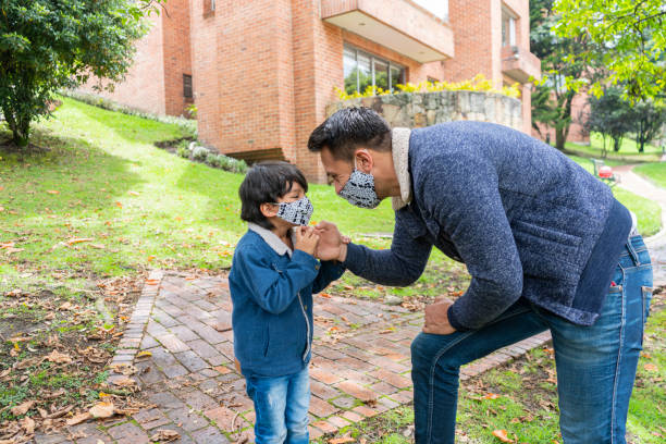 istock dad helps his little son put on his mask 1255215442