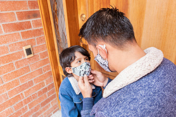 istock dad helps his little son put on his mask 1255215492