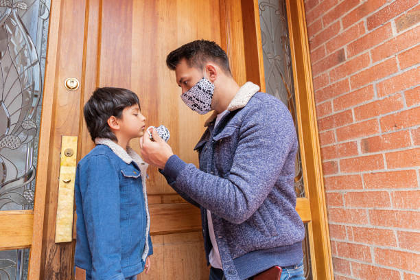 istock dad helps his little son put on his mask 1255215518