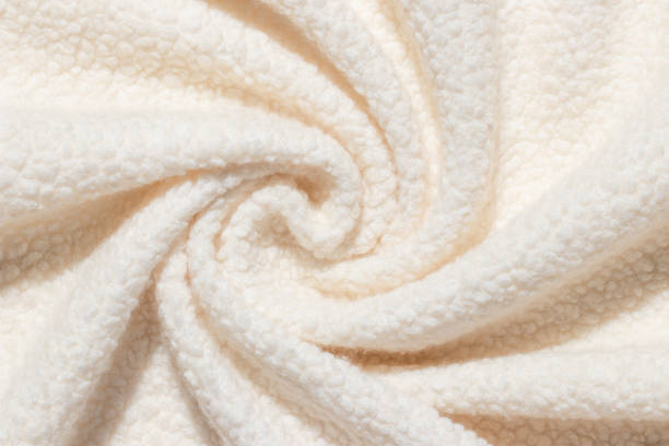 Beige background wool texture swirled into spiral pattern. Sheep fluffy warm fur. Tender twisted surface