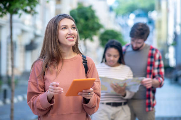 istock Young girl in sweater with tablet looking at building 1255218913